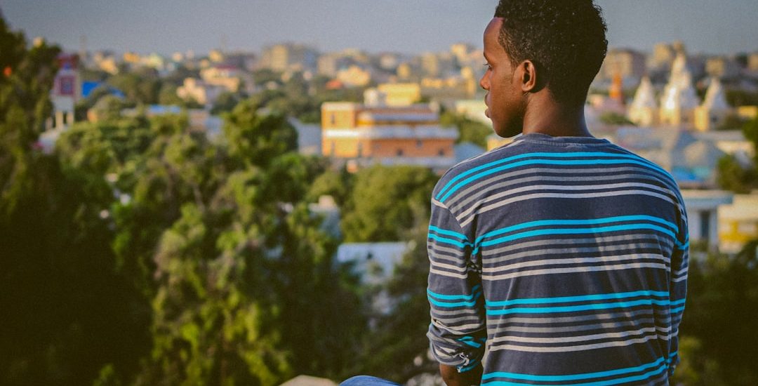 a man sitting on a ledge overlooking a city