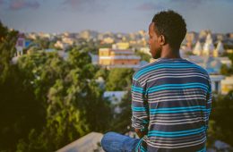 a man sitting on a ledge overlooking a city