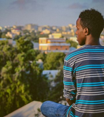 a man sitting on a ledge overlooking a city